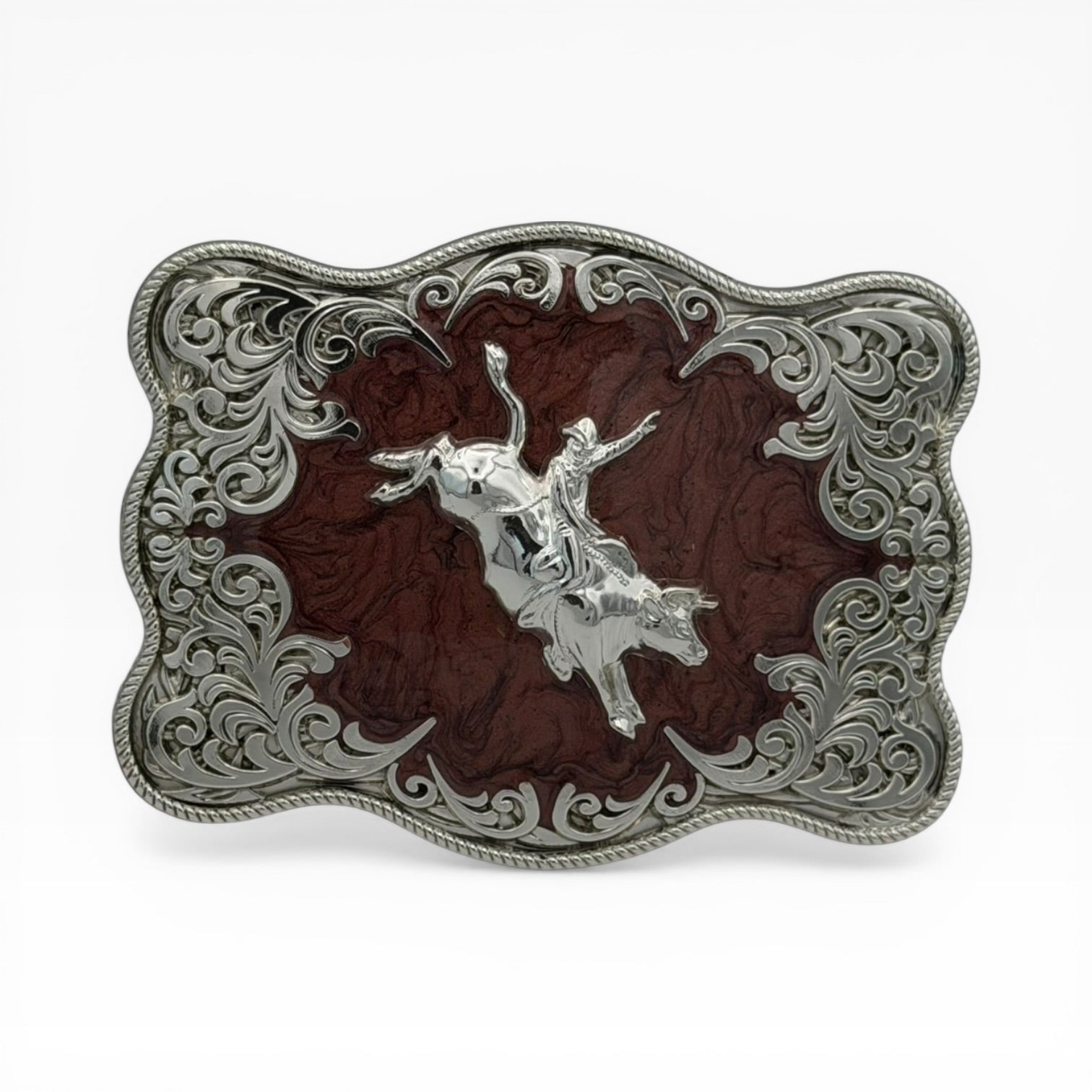Silver bull rider buckle with mahogany wood-tone background, ornate filigree, and rope edge.