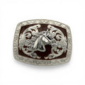 Silver tone western buckle with detailed horse head, scrollwork, and a deep brown background.