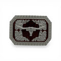 Silver longhorn skull buckle with dark woodgrain background, western scroll engravings, and rope edge.
